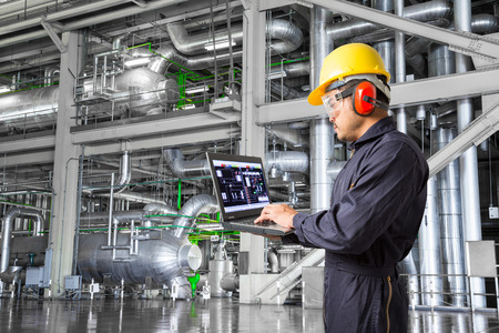Engineer using laptop computer for maintenance equipment and pipeline system in thermal power plant factoryの写真素材