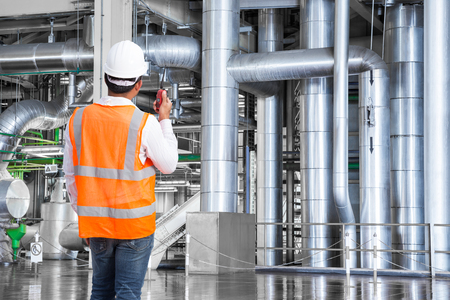 Engineer working in a thermal power plant with talking on the walkie-talkie for controlling workの写真素材