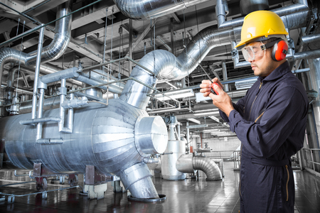 Engineer working in a thermal power plant with talking on the walkie-talkie for controlling workの写真素材