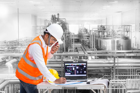 Industrial engineer checking machine status with laptop computerの写真素材