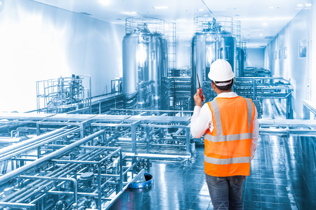 Industrial engineer working in the factory with talking on the walkie-talkie for controlling workの写真素材