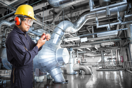 Engineer working in a thermal power plant with talking on the walkie-talkie for controlling workの写真素材