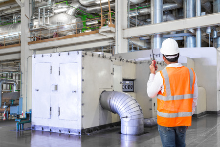 Engineer working in the thermal power plant with talking on the walkie-talkie for controlling workの写真素材