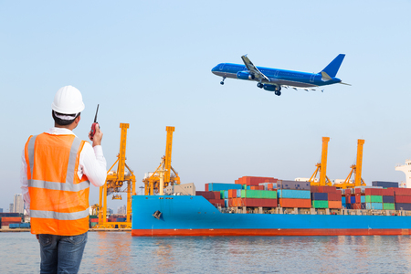 Dock worker talking on the walkie-talkie for controlling loading container in an industrial harborの写真素材