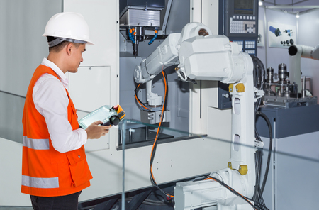 Engineer controlling automatic robotic hand machine tool with CNC machine in automotive industryの写真素材