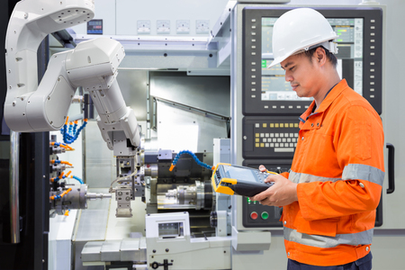 Maintenance engineer programing automated robotic with CNC machine in an industryの写真素材