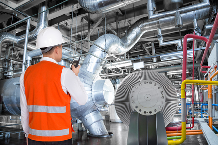 Maintenance engineer working in thermal power plant with talking on the walkie-talkie for controlling workの写真素材