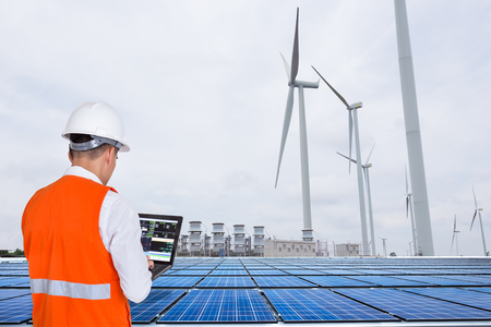 Electrical engineers working at wind turbine power generator station with solar panel, energy conceptの写真素材