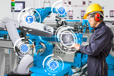 Engineer using laptop computer for maintenance automatic robotic hand machine tool at industrial manufacture factoryの写真素材