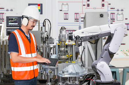 Engineer using laptop computer for maintenance automatic robotic hand machine tool in automotive industryの写真素材