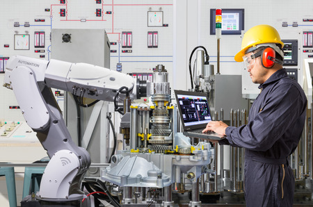 Engineer using laptop computer for maintenance automatic robotic hand machine tool in automotive industryの写真素材