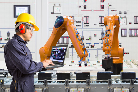 Engineer using laptop computer for maintenance automatic robotic hand machine tool in smart factory,...