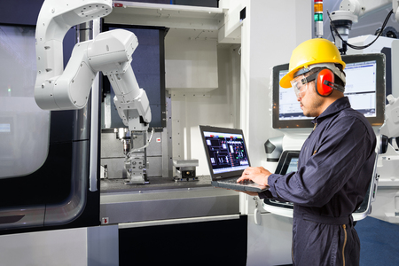 Maintenance engineer using laptop computer control automatic robotic hand with CNC machine in smart factory, Industry 4.0 conceptの写真素材