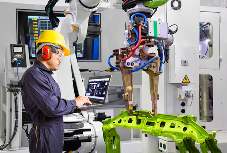 Maintenance engineer using laptop computer control robot grip automotive workpiece in smart factory, Industry 4.0 conceptの写真素材