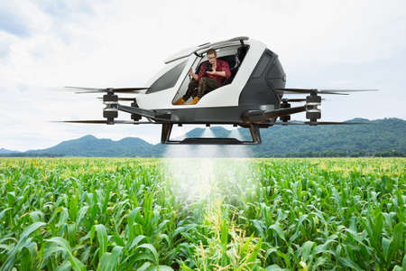 Agriculture autonomous aerial vehicle driving to spray fertilizer on corn fields with farmer...