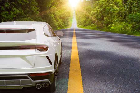 White car running along the road natural path in the sunriseの写真素材