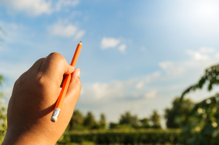 pencil in left hand and blue skyの写真素材