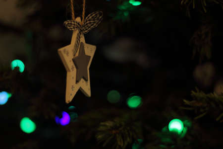Ornament star hanging on fir with Christmas lights in the backgroundの写真素材