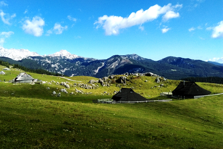 on a green hill there are houses on the background of snow-capped mountains and a beautiful skyの写真素材