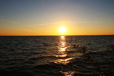 Beautiful sunset on the shore of a blue calm lake, background.の写真素材