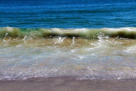 A beautiful wave of the Pacific Ocean rolls on the beachの写真素材