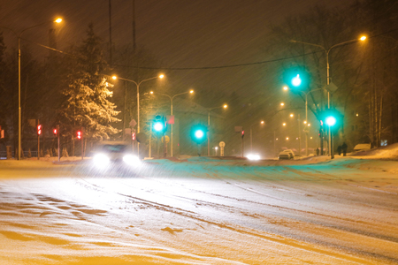 Snowy winter road with cars driving on roadway in snow stormの写真素材