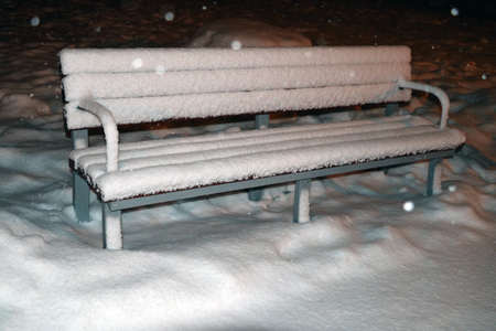 Snow-covered bench in the evening parkの写真素材