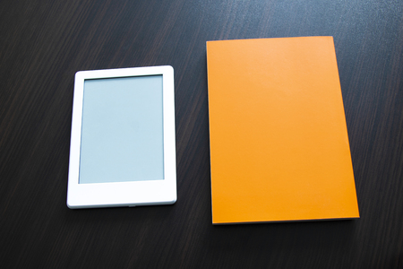 E-book and paper book on the table. Concepts of self-educationの写真素材