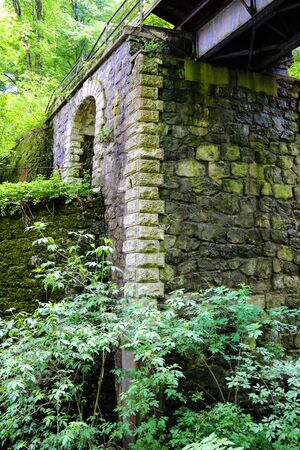 The pillar of the old bridge of stones surrounded by forestの写真素材