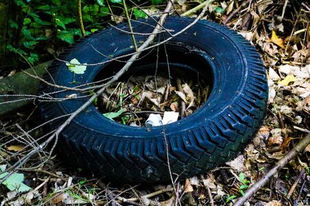 The old cracked tire from the wheel lies in a landfillの写真素材