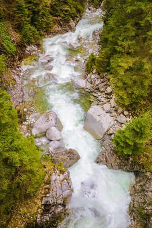 Top-down drone view of rapids of mountain river with wet boulders and pebble shoreの写真素材