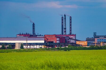 Fumes of a mining plant against the sky and green grassの写真素材