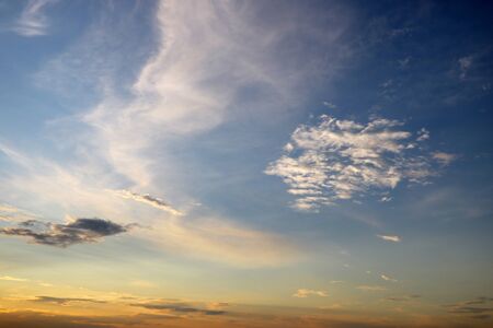 Sky blue and orange light of the sun through the clouds in the skyの写真素材