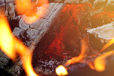 Beautiful color of burning red coals and black charred wood. Orange hot coals in the Russian stove. Red burning coals as a texture for designの写真素材