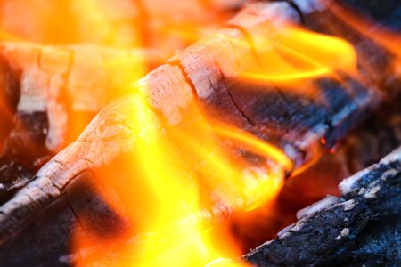 Beautiful color of burning red coals and black charred wood. Orange hot coals in the Russian stove. Red burning coals as a texture for designの写真素材