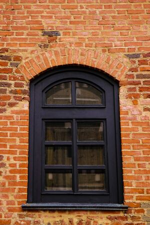 Old window on the background of a yellow brick wallの写真素材