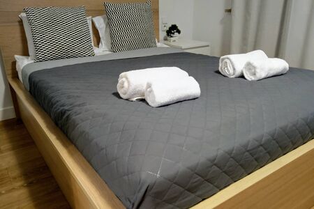 View of the made-up bed with pillows in the bedroom with towels on itの写真素材