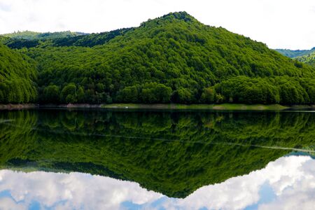 View of the high green hill, mountain. Reflection in water. Out of focus. A clear sunny day. Nature backgroundの写真素材