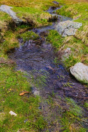 Mountain stream flows along the mountainside, snow. Nature background in spring or summer. Selective focusの写真素材