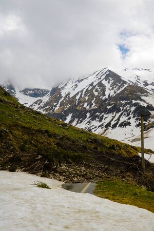 Mountain road littered with snow and trees. The convergence of an avalanche of snow. Clearing the roadの写真素材