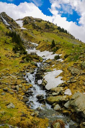 Mountain stream flows along the mountainside, snow. Nature background in spring or summer. Selective focusの写真素材