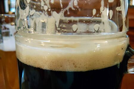 Mug of dark beer with foam on the table, selective focusの写真素材