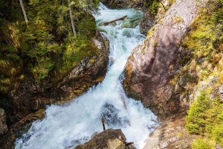 Powerful stream of mountain river running down the valley among alpineの写真素材