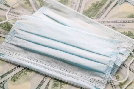 Coronavirus epidemic concept. Medical protective mask on dollars banknotes. There is a place for copyspaceの写真素材