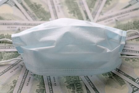 Medical mask on on dollars as a symbol of increasing prices for protecting the respiratory tract from the virus. There is a place for copyspaceの写真素材