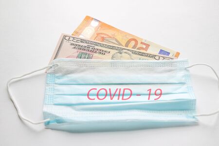 Medical mask on euro banknotes and dollars. Concept of increasing prices for protecting the respiratory tract from the virusの写真素材