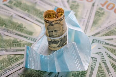 Medical mask on dollars as a symbol of increasing prices for protecting the respiratory tract from the virus. There is a place for copyspaceの写真素材