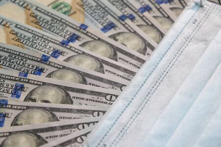 Medical mask on dollars as a symbol of increasing prices for protecting the respiratory tract from the virus. There is a place for copyspaceの写真素材