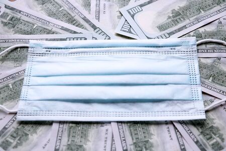 Coronavirus epidemic concept. Medical protective mask on dollars banknotes. There is a place for copyspaceの写真素材