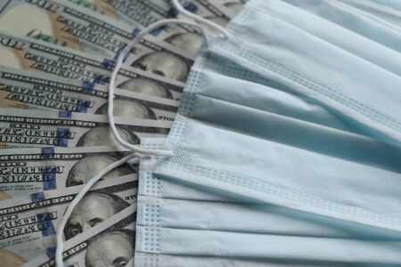 Medical mask on dollars as a symbol of increasing prices for protecting the respiratory tract from the virus. There is a place for copyspaceの写真素材